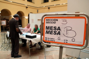 Un cartel indicativo y de un elector votando en uno de los colegios electorales de la ciudad de Tarragona.