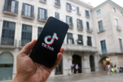 En primer terme, un mòbil amb el logotip d'una xarxa social; al fons, la façana de l'Ajuntament de Girona.