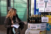 Pla mitjà d'una treballadora de l'adminstració de loteria del centre comercial Arenas de Barcelona preparant ampolles de cava per celebrar que el local ha repartit el segon premi del sorteig de Reis.