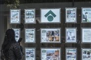 Una dona mirant els anuncis d’habitatges exposats en una immobiliària.