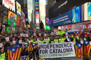 Fotografia de diversos corredors de la Marató de Nova York a Times Square amb estelades i pancartes demanant l'alliberament dels presos polítics.