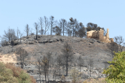 Un edifici abandonat amb els efectes de l'incendi de la Ribera d'Ebre al fons entre la Palma i Vinebre