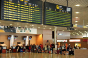 Pantalla indicant un retard en un vol de Ryanair a Frankfurt i cues de fons a l'Aeroport de Reus.