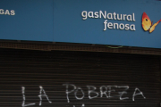 Un home passa per davant de la reixa de la seu de Gas Natural a Reus, acabada de pintar amb un grafit on s'hi llegeix "la pobresa energètica mata". Imatge del 19 de novembre de 2016