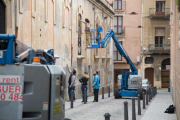 Un graffiter pintant una de les finestres tapiades del carrer de Pere Òdena.