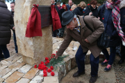 Un home posa un clavell roig al monument que commemora els Fets de la Fatarella.