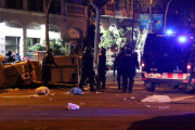 Pla general d'agents antidisturbis dels Mossos d'Esquadra retirant contenidors tombats al mig del carrer a Barcelona durant els aldarulls posteriors a la manifestació del 25 de març