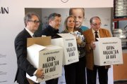 Marc Simón, Joan Roca, Marta Peris i Frederic Gómez Pardo agafant les caixes per la recollida de llet durant la presentació de la campanya 'Cap nen sense bigoti'.