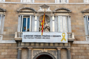 Part central de la façana del Palau de la Generalitat amb la pancarta amb el llaç groc penjats.