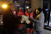 Pla americà de voluntaris de la Creu Roja lliurant una manta i un got de caldo a en Francisco Moreno, un sensesostre que passa la nit en un caixer de Tarragona. Imatge de l'11 de gener del 2018