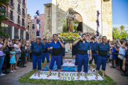 Els portadors de la imatge, aturats damunt la catifa de flors i, al fons, dos pilars dels castellers.