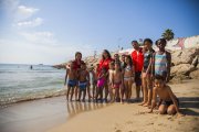 Fotografia família dels nens del casal d'estiu amb els monitors de Creu Roja, ahir, a la platja del Miracle.