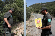 Dos efectius dels Agents Rurals a punt de col·locar un cartell que indica que està prohibit accedir a la serra del Montsec.