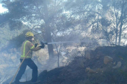 Un bomber amb la mànega treballant a l'incendi.