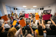 Pla general del ple aquest dissabte 15 de juny amb les protestes dels veïns i les dues fotografies de Puigdemont i Torra al fons