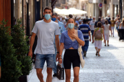 Un chico y una chica andando con mascarilla por la calle Monterols de Reus.