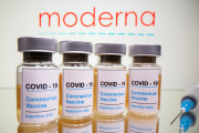 Vials amb un adhesiu que diu «COVID-19 / Vacuna contra el coronavirus / només per injecció" i una xeringa davant del logotip de Moderna en