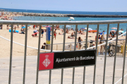 Pla obert de la platja Nova Icària de Barcelona amb una tanca en primer pla.