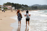 Dues dones d'esquenes caminant a la platja Llarga de Tarragona en l'últim dia de la fase 1.