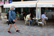 Pla general de la terrassa d'una cafeteria a Calafell Platja mentre un home passeja amb mascareta.