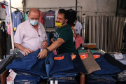 Un paradista i un client comprant en una de les parades de roba del mercat de Bonavista que ha reobert després de tres mesos d'inactivitat.