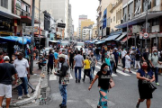 Decenas de personas caminan en una concurrida vía comercial en el centro de Sao Paulo (Brasil).