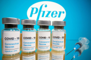 Vials amb l'etiqueta 'COVID-19 / vacuna contra el coronavirus / només per injecció' i una xeringa mèdica davant del logotip de Pfizer