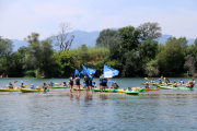 Els participants en la 20a Piraguada en Defensa de l'Ebre a la seva arribada a Tortosa, rodejant els activistes que han fet l'acció reivindicativa.