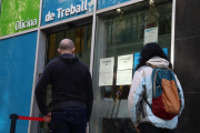 Pla mijtà de dues persones esperant per entrar a l'Oficina de Treball.