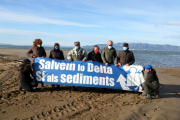 Activistas de l'Associació Sediments con una pancarta reivindicativa antes de comenzar la acción visual para denunciar la fragilidad de la barra del Trabucador.