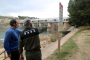 El cap dels Agents Rurals a l'Ebre, Miquel Àngel Garcia, i el biòleg del Grup Natura Freixe, Arnau Pou, assenyalant els marges de la presa de Flix.