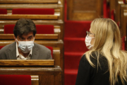 Pla del líder d'ERC al Parlament, Sergi Sabrià, assegut al seu escó del Parlament mentre la diputada i regidora de JxCat Elsa Artadi puja les escales de l'hemicicle