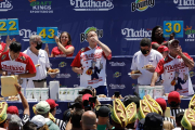 Joey Chestnut en el centro de la imagen compitiendo con dos rivales más.