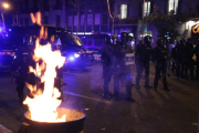 Agents dels Mossos d'Esquadra al costat d'una paperera en flames durant els aldarulls posteriors a una manifestació dels CDR pel quart aniversari de l'1-O.