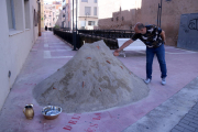 El artista Àlvar Calvet cogiendo una de las monedas del suelo incrustadas en su obra efímera 'Guanyar terreno' al lado del canal de la Dreta, en Amposta.