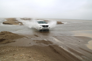 Un vehicle creua dins l'aigua un dels punts en què la barra del Trabucador s'ha trencat pel temporal.