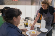 Roser, treballadora del Centre Social del Roser, i els seus companys serveixen el dinar als usuaris.