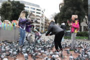 Unes turistes interactuen amb els coloms de Plaça Catalunya mentre es fan fotos.