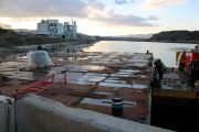 Operarios en una de las barcazas que se utilizarán en el proceso de restitución de la zona descontaminada del pantano.