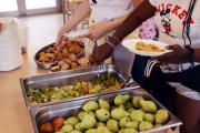 Imatge d'arxiu de dues alumnes servint-se el dinar en un plat.