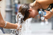 Una dona es refresca en una font per a combatre la calor.