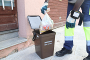 Pla tancat d'un operari traient una bossa d'escombraries del cubell de la fracció orgànica en una recollida porta a porta.