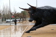 Una persona passa al costat de la figura del bou de l'escultura d'homenatge a l'afició taurina que presideix una rotonda a Amposta.
