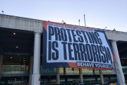 Òmnium desplega una pancarta gegant a l'aeroport del Prat amb el lema: 'A Espanya, protestar és terrorisme'