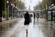 Una dona d'esquenes amb un paraigua caminant per la Rambla de Tarragona.