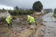 Uns operaris netejant la carretera d'accés a Manuel tallada per la DANA.