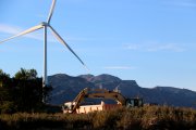 Una màquina i un camió treballen davant d'un dels molins de vent de la Collada del Perelló.