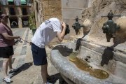 Un jove es refresca en una de les fonts de les escales de la catedral de Tarragona buscant alleujar les altes temperatures.