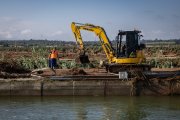 Un operari treballant amb una màquina excavadora al canal dret de l'Ebre després dels aiguats
