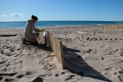 Una investigadora de la UdG col·loca un cartell informatiu en un dels captadors eòlics de la platja de Calafell.
